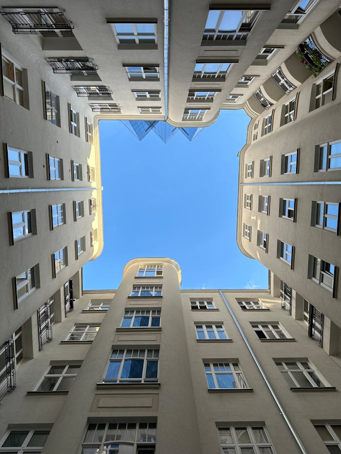 Crafting Captivating Headlines: Your awesome post title goes here Upward view of a symmetrical urban courtyard with a clear blue sky visible above.