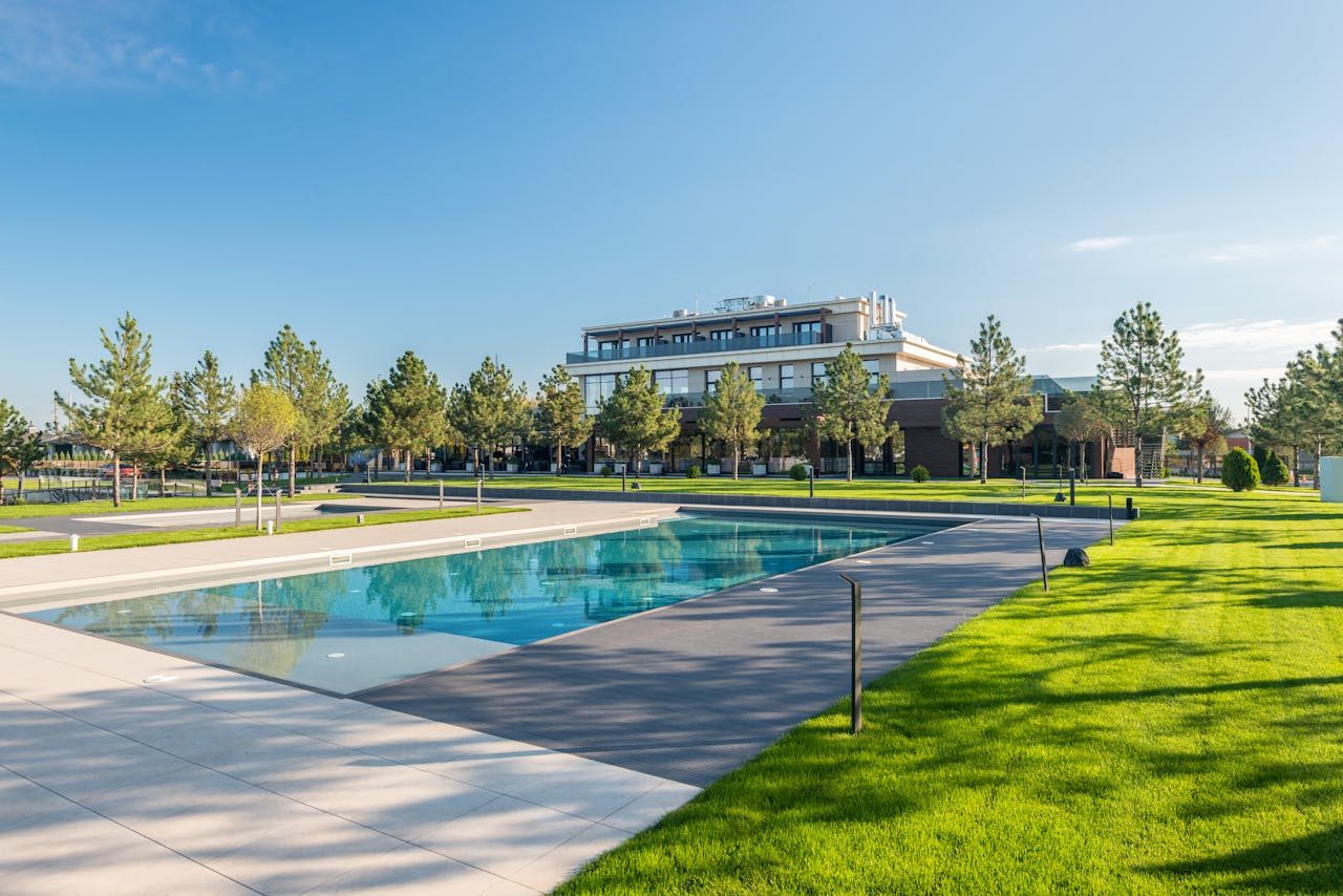 Home Elegant poolside at a modern resort with lush greenery and clear blue skies, ideal for luxury travel.
